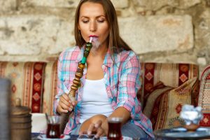 Woman Smoking A Hookah And Uses Smartphone In A Cafe In Istanbul, Turkey